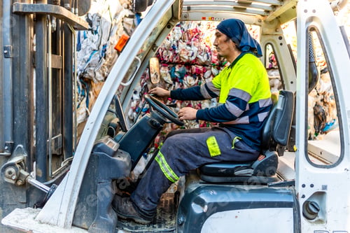 Preview: Man moving plastic bales driving forklift in a recycling plant