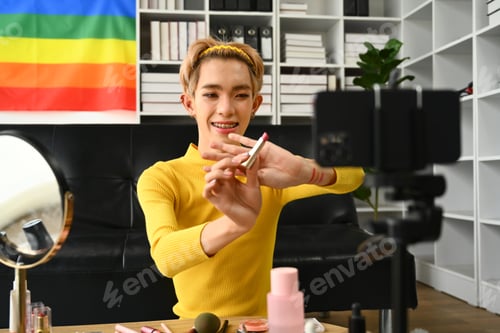 Preview: Smiling Asian gay man blogger filming daily makeup routine tutorial on smartphone.