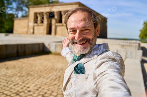 Preview: Smiling man taking a selfie with ancient stone temple in the background