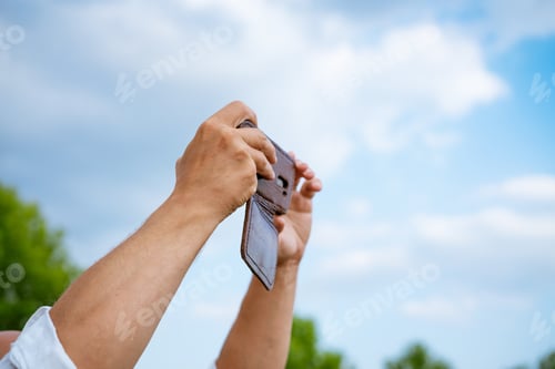 Preview: a man takes pictures on the phone against the background of the sky, close-up
