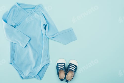 Preview: top view of baby bodysuit and shoes isolated on blue