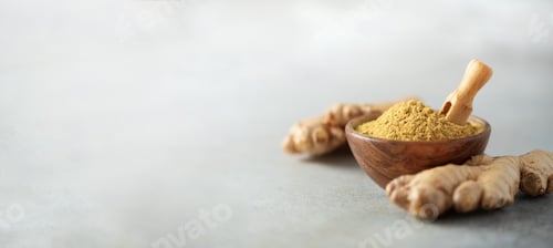 Preview: Ginger root and ginger powder in wooden bowl over grey concrete background with copy space. Immune