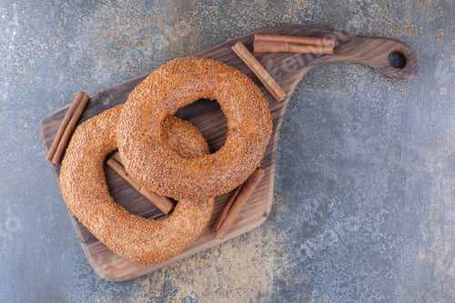 Preview: Bagels and cinnamon sticks on a wooden board on marble background