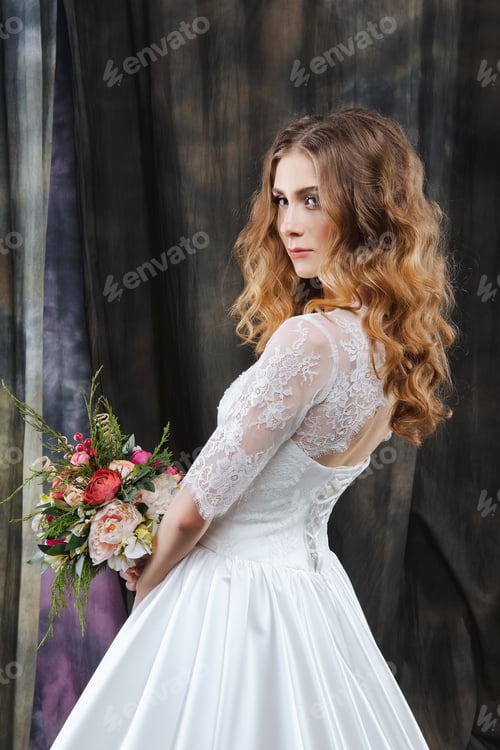Preview: Bride in White Dress Holding Flowers Looking Back