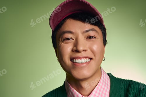 Preview: Stylish asian man smiles brightly in a vibrant green studio setting