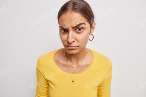 Vista previa: Serious woman raises eyebrows looks skeptical at camera reacts on something wears earrings and casua