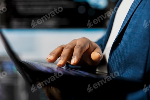 Preview: Black coder focused on programming with laptop at a digital workstation