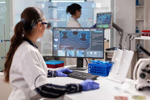 Preview: Biologist doctor checking DNA informations typing on pc