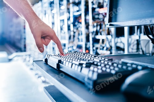 Preview: IT specialist pressing red button on keyboard in big data center.