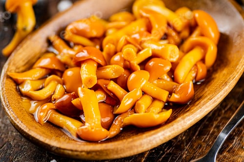 Preview: Marinated mushrooms on a wooden plate.