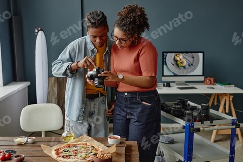 Preview: Young Adult Black Woman and Black Man Reviewing Camera Settings during Food Shoot