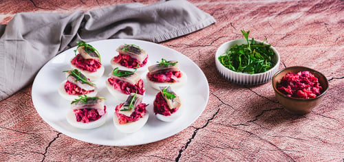 Preview: Egg halves stuffed with herring under a fur coat on a plate on the table web banner