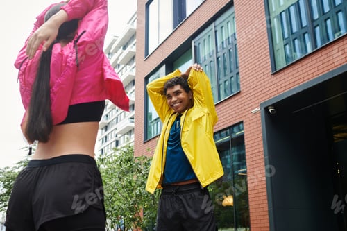 Preview: Young athletes stretch and prepare for training in a vibrant urban environment during morning