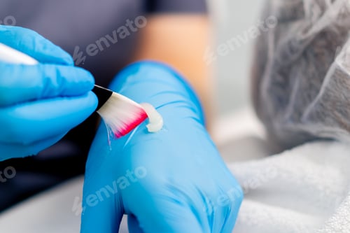 Vista previa: doctor's hand in gloves holding a brush and applying a mask to check the consistency in beauty salon