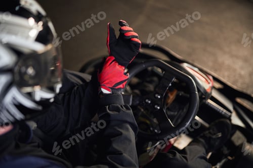 Preview: top view of go kart racer in helmet wearing red sport gloves, preparing for competition concept