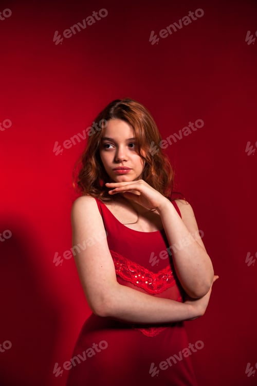 Preview: Portrait teen cover girl with curly hair posing in stylish red dress on red