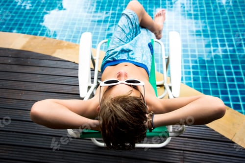 Preview: Young caucasian boy enjoying sunbathing by the pool
