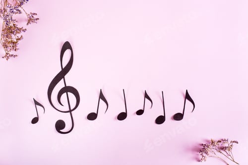 Preview: Paper musical clef and notes in a row and dried flowers on a pink background. Top view.