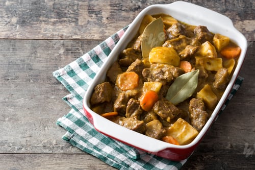 Preview: Delicious beef stew with potatoes and carrots, garnished with bay leaves, simmering in a baking dish