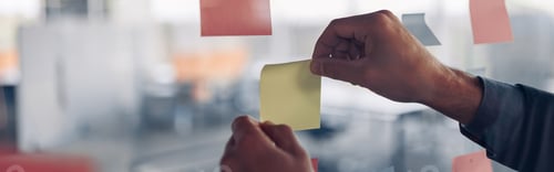 Preview: Businesswoman hand's is sticking sticky notes on motivation board in office