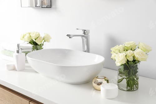 Preview: White sink between beautiful roses and toiletries in bathroom