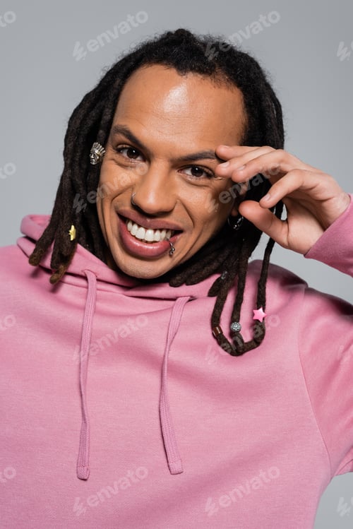 Preview: portrait of happy multiracial man in pink hoodie looking at camera isolated on grey