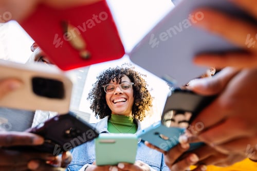 Preview: Happy group of young people using mobile phones outdoors.