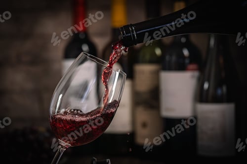 Preview: Pouring Red Wine into Glass with Bottles and Grapes