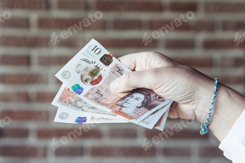 Preview: Woman holding pounds sterlings against background