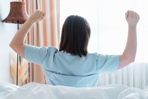 Preview: Young woman goes to window and stretches his arms, rear view.