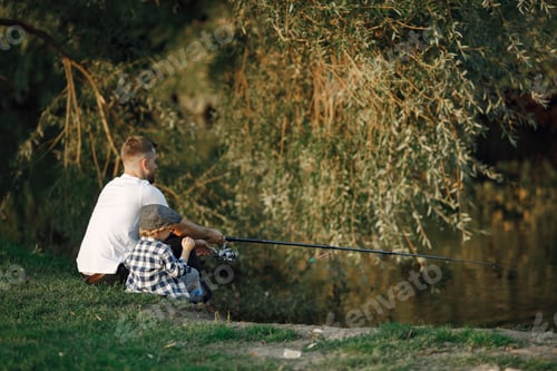 Preview: Young father fishing together with his little toddler son near the river