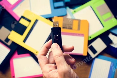 Preview: Hand holding USB drive with floppy disk background