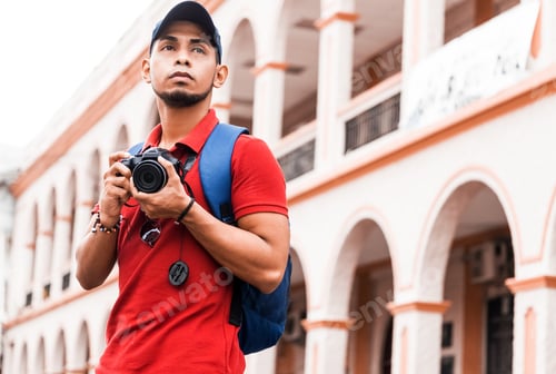 Preview: Handsome beard man in a red shirt and backpack taking photography.Traveler photographer concept