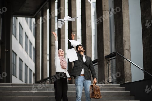 Preview: Cheerful arabian man and woman throwing up documents