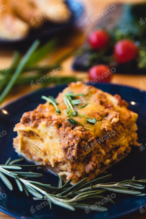 Preview: Piece of tasty hot lasagna with red wine. Selective focus