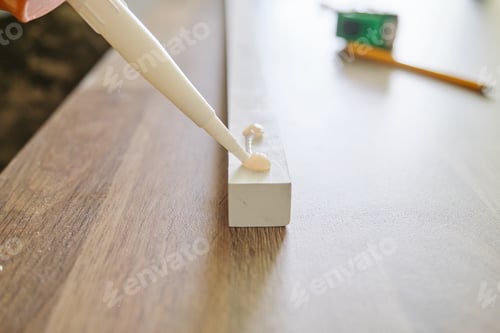Preview: Carpenter male using construction glue when working with wooden board
