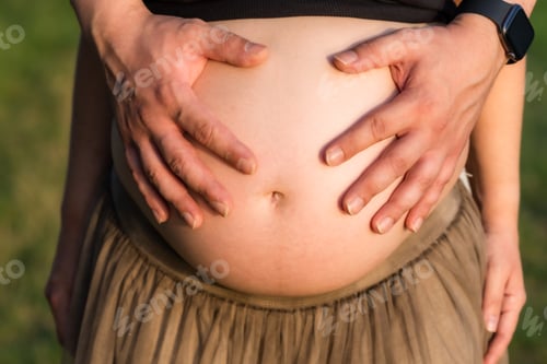 Preview: Close-up view of the hands of a man on the belly of a pregnant woman outdoors