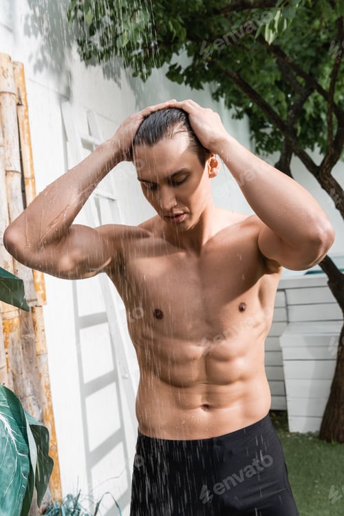 Preview: athletic man touching wet hair while taking shower outdoors