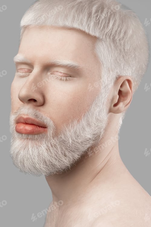 Preview: Portrait of young albino man with closed eyes, white hair and pale skin posing on grey studio