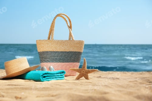 Preview: Stylish beach accessories on sand near sea. Space for text