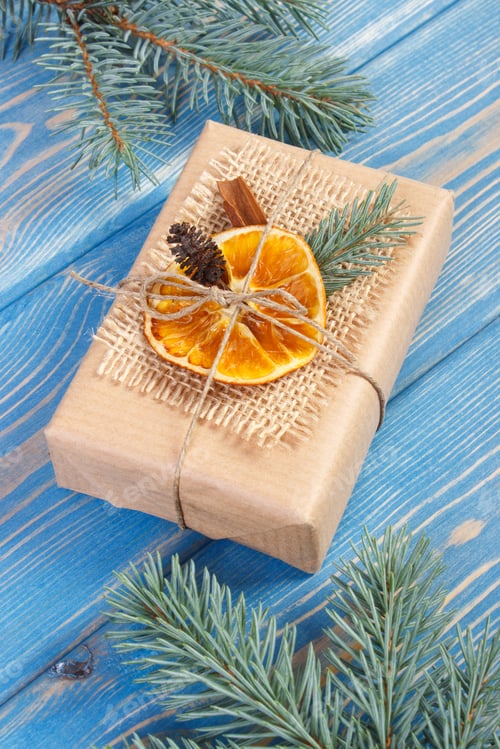 Preview: Wrapped Gift with Natural Decorations on Blue Table