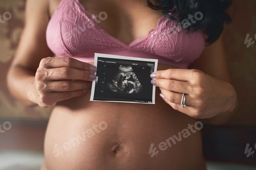 Preview: Cropped shot of an unrecognizable pregnant woman standing in her bedroom at home