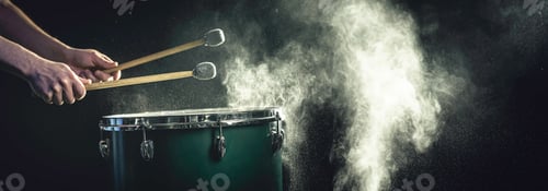 Preview: A man plays a musical percussion instrument with sticks on a dark background.