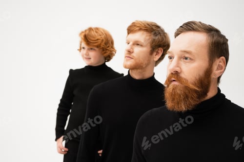 Preview: adult bearded men and redhead boy in black turtlenecks looking away isolated on grey