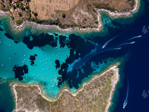 Preview: Aerial view of a turquoise lagoon with numerous boats floating on clear water, surrounded by dark