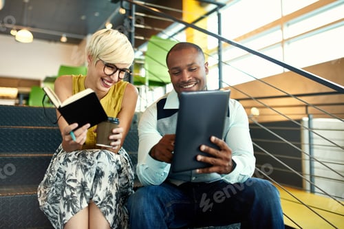 Preview: Two creative millenial small business owners working on social media strategy on a staircase