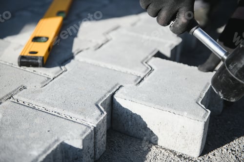 Preview: The master in gloves lays paving stones in layers