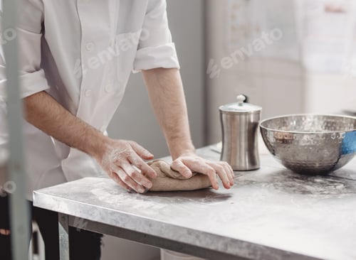 Preview: Baker kneads dough on the table in the bakery