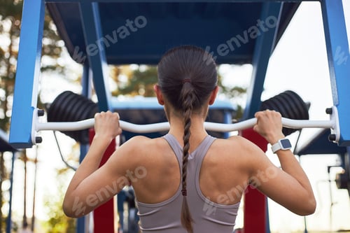Preview: Young Adult Woman Exercising on Outdoor Gym Equipment during Workout