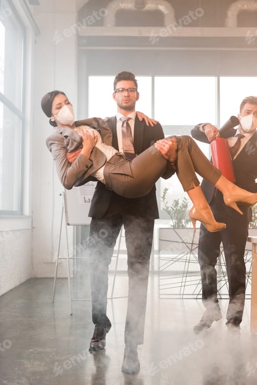 Preview: handsome businessman in glasses holding in arms female coworker with closed eyes near colleague